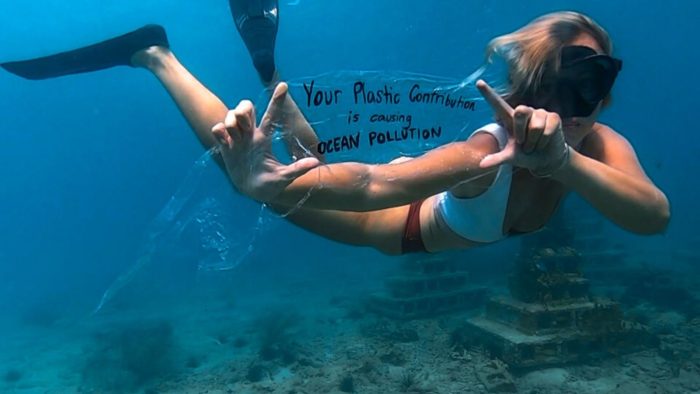 在水下游泳的女孩举着塑料污染标语